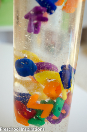 Alphabet sensory bottle with letter beads floating inside and collecting at the bottom