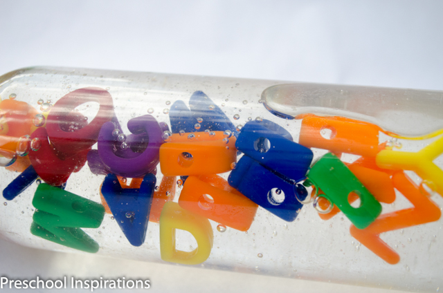 alphabet sensory bottle laying on its side with the alphabet beads floating to the top