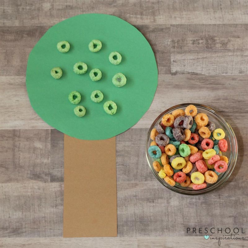 green fruit loops placed on a tree made of construction paper made to look like apples