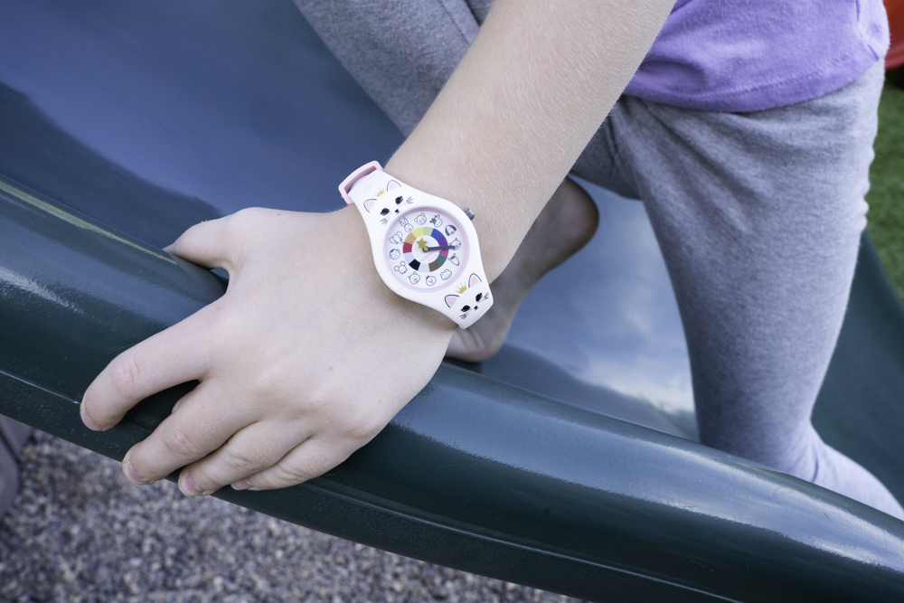 Child climbing slide while wearing cat watch.