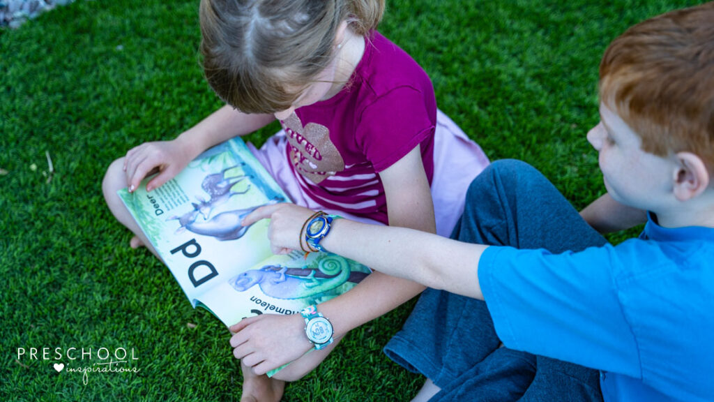 Two kids wearing digital watches and reading a book