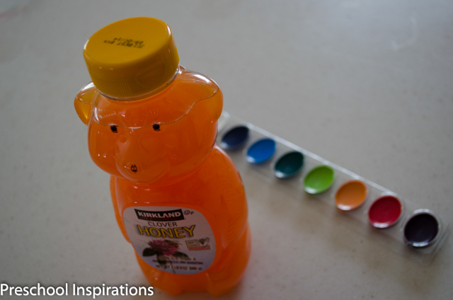 a honey bear sitting in front of a row of crayola watercolor cakes