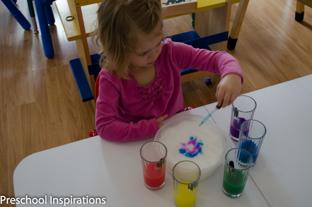 a preschool girl paining on snow with liquid watercolors