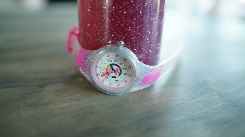 a unicorn time telling watch wrapped around a glitter sensory jar